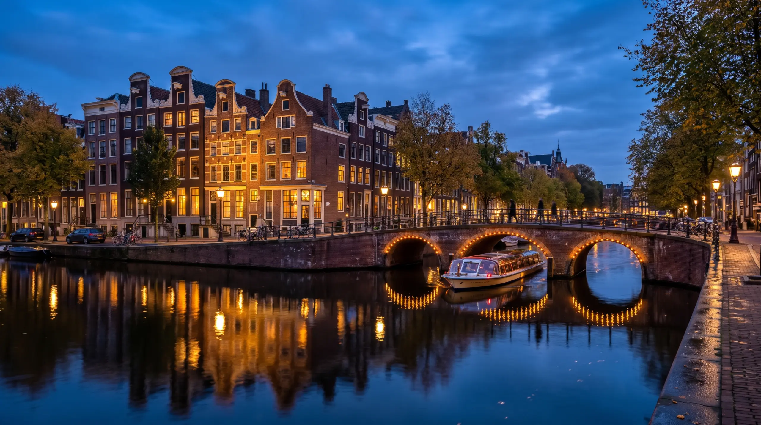 Londres con Bélgica y Ámsterdam 1 Canales de Ámsterdam en la hora azul, con casas de fachadas escalonadas y un puente iluminado