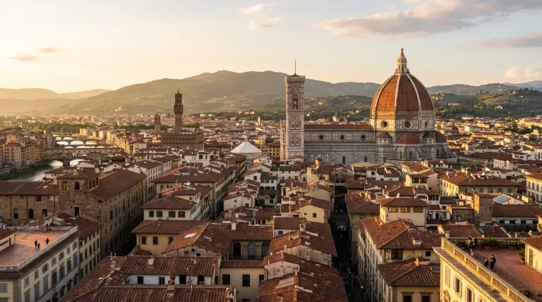 The Florence cathedral dome rising above terracotta rooftops at golden hour, with the Tuscan hills behind